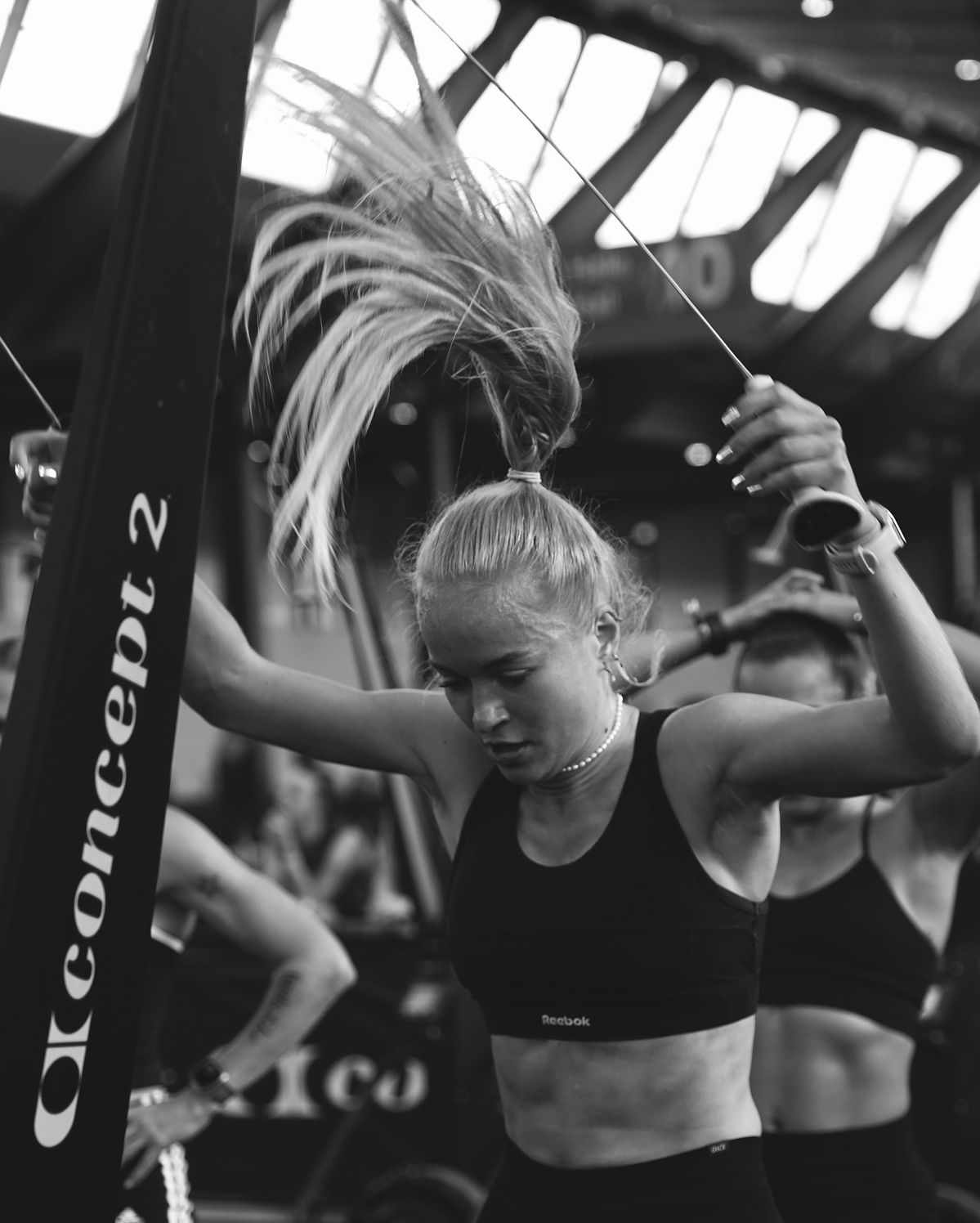 Black and white photo of a man in a gym with barbell and 'Strong' box.